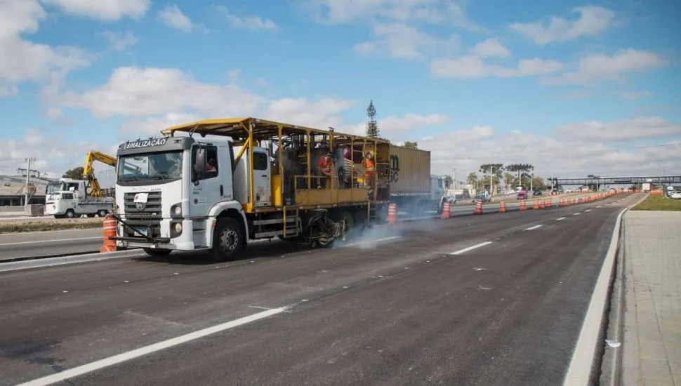 Imagem mostra um caminhão pintando as faixas das pistas do novo viaduto de Curitiba.