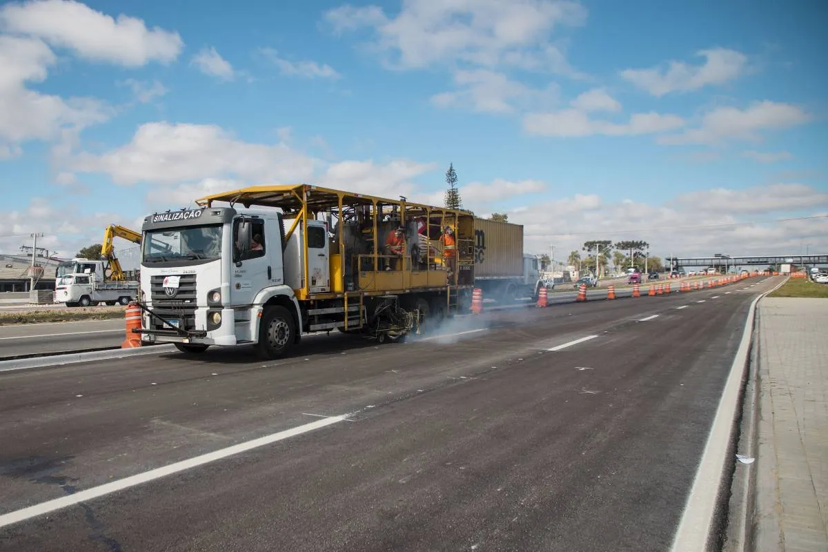 Imagem mostra um caminhão pintando as faixas das pistas do novo viaduto de Curitiba.