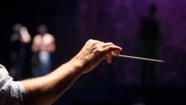 Imagem mostra a batuta de um maestro.