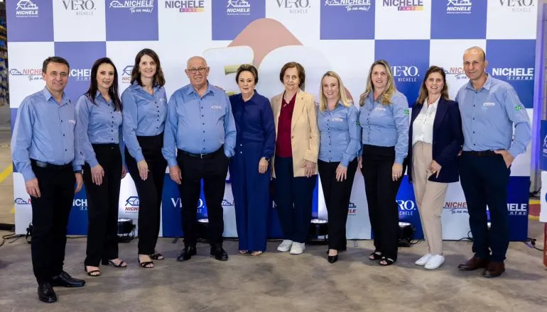 Grupo de pessoas com uniforme de empresa posando para foto / Nichele Materiais Para Construção completa 50 anos
