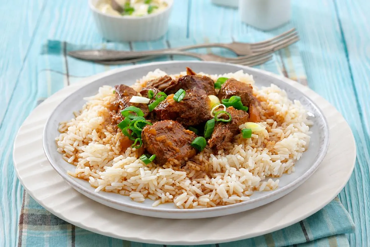 Imagem mostra um prato com picadinho de carne e arroz.