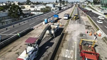 Imagem de drone mostra as obras no complexo Taruma, com máquinas trabalhando, muitos cones, caminhões e carros passando nas faixas das extremidades.