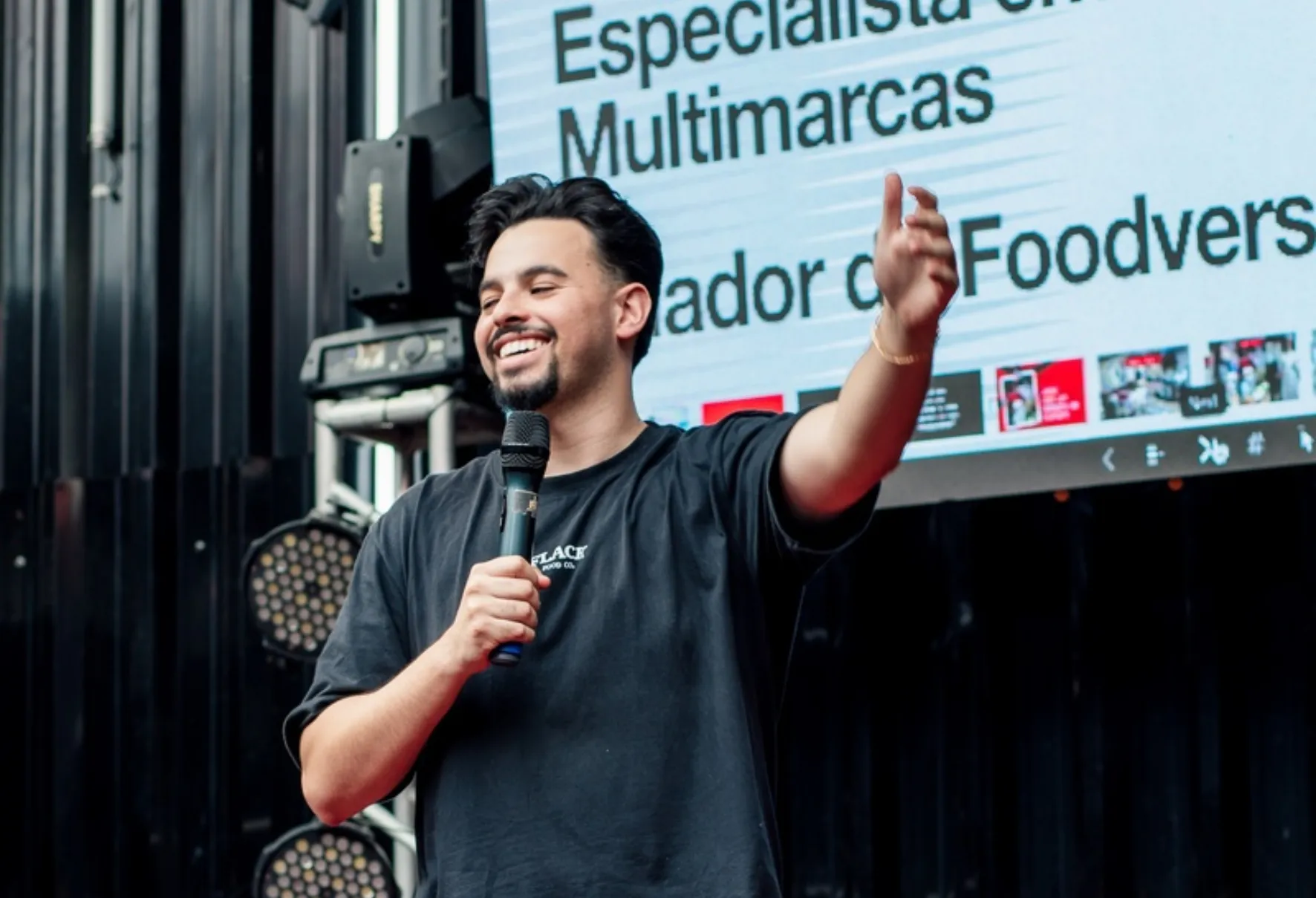 Jovem de camiseta preta e microfone nas mãos discursando em palco / Jovem empreendedor de Curitiba vai dos R$ 10 mil ao R$ 1 milhão mensais.