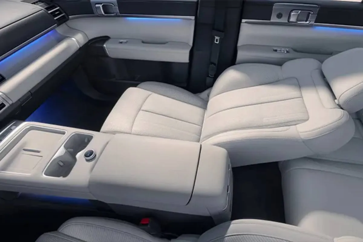 Imagem mostra o interior do BYD TI 7 com bancos brancos e tela multimídia de 15,6 polegadas.