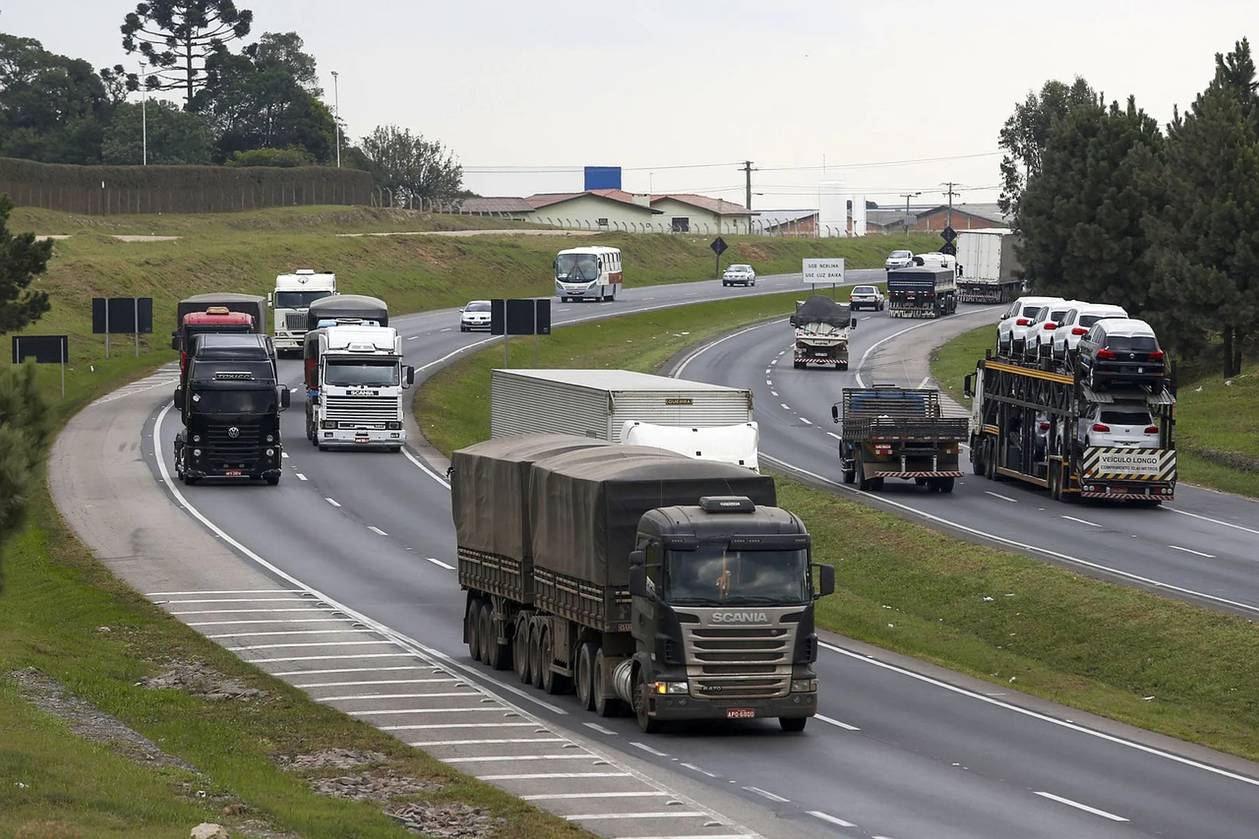 imagem mostr auma curva de estrada, com vários caminhos e carros transitando