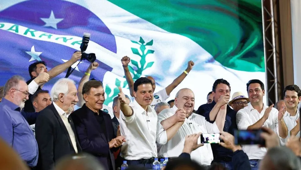 foto mostra diversas lideranças, entre eles o governador Ratinho Junior e o prefeito de Curitiba, Eduardo Pimentel, junto com Sandro Alex, Rafael Greca e Álvaro Dias em cima de um palco, com a bandeira do Paraná num telão ao fundo
