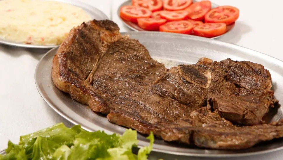 Imagem mostra um filé de igreja bem assado servido em uma bandeja de alumínio com maionese, tomate e alface.