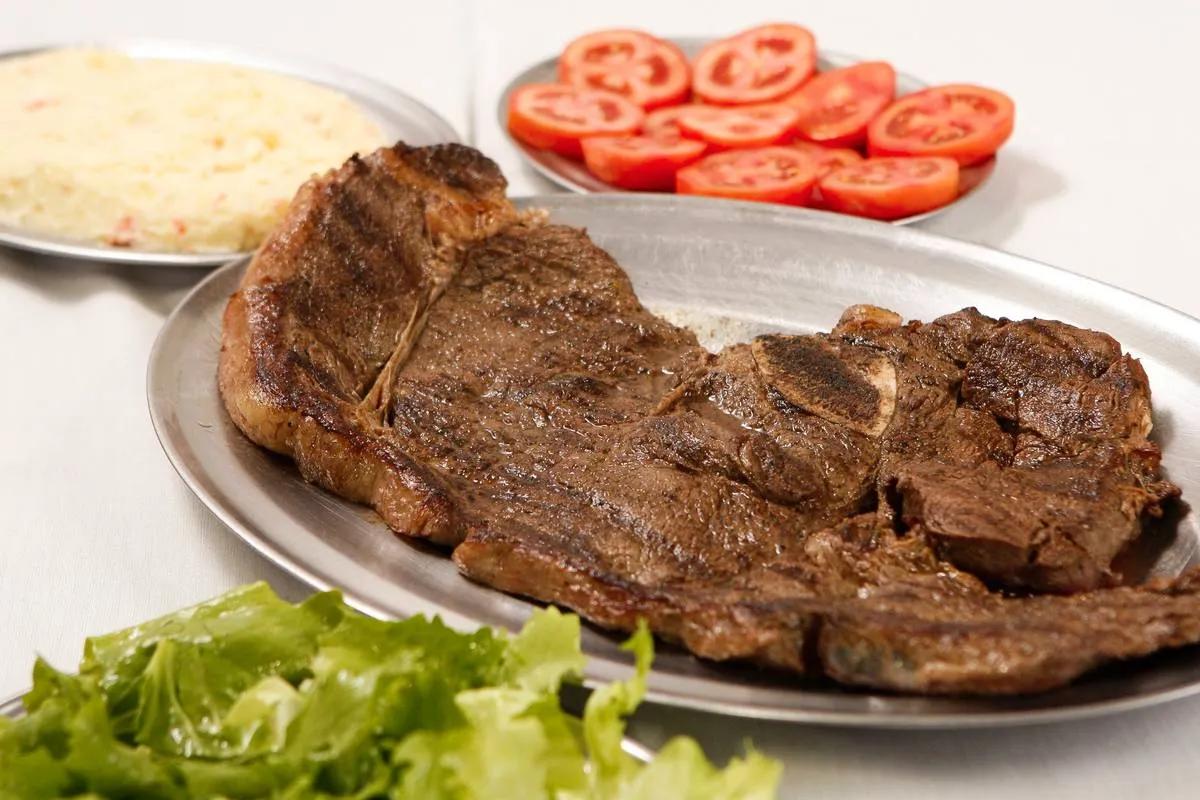 Imagem mostra um filé de igreja bem assado servido em uma bandeja de alumínio com maionese, tomate e alface.