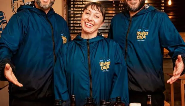 Cervejas artesanais de Guarapuava / três irmãos (dois homens e uma mulher ao centro) posando com as cervejas produzidas por sua cervejaria
