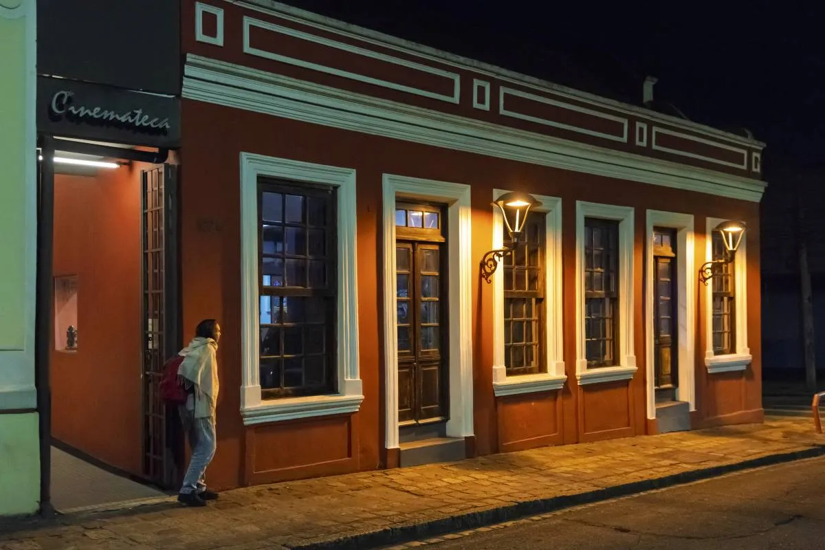 Imagem noturna mostra a fachada da Cinemateca, em Curitiba, com iluminação artística.
