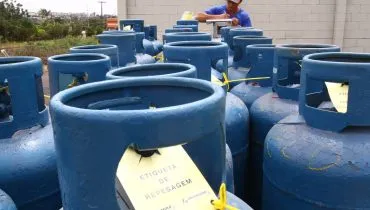 Imagem mostra um caminhão carregado com botijões de gás de cozinha na cor azul escuro.