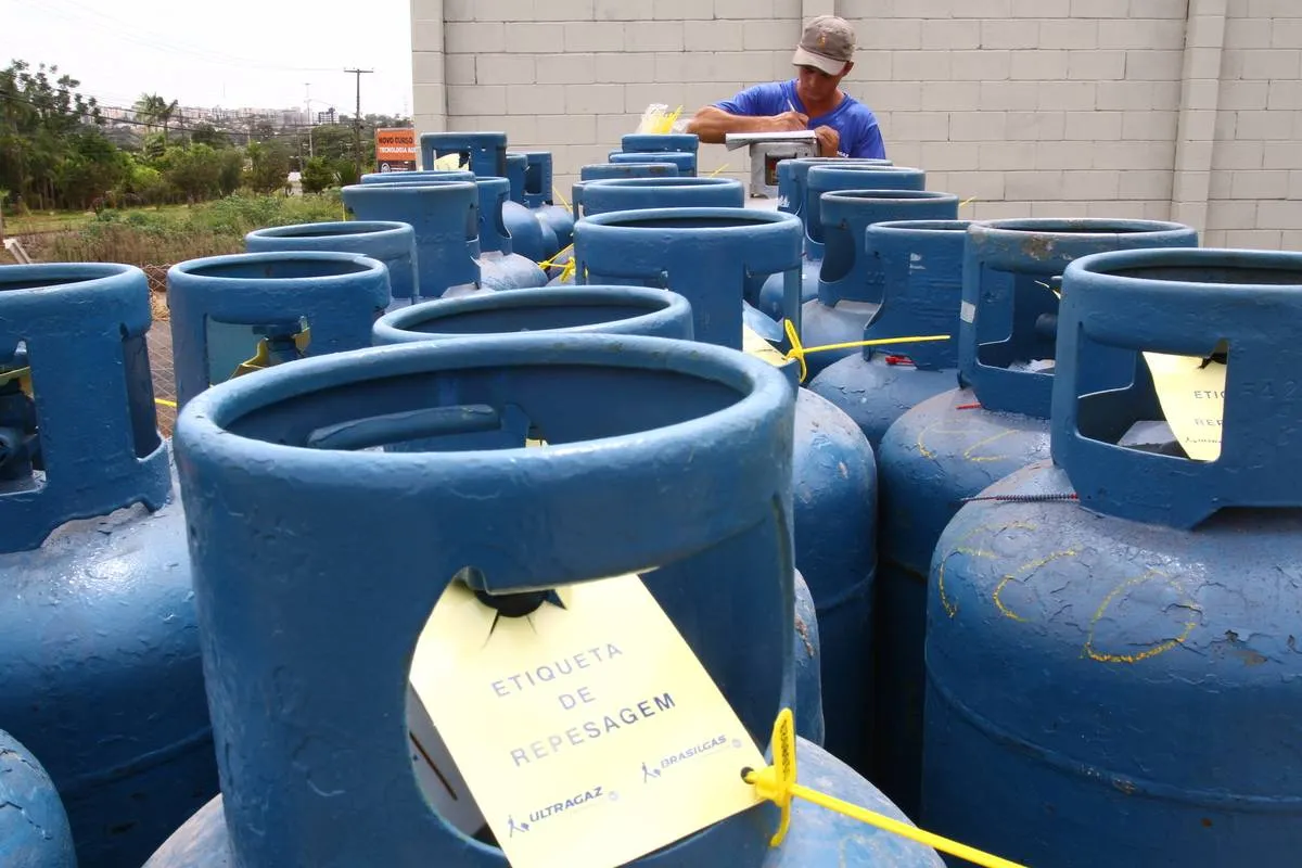 Imagem mostra um caminhão carregado com botijões de gás de cozinha na cor azul escuro.