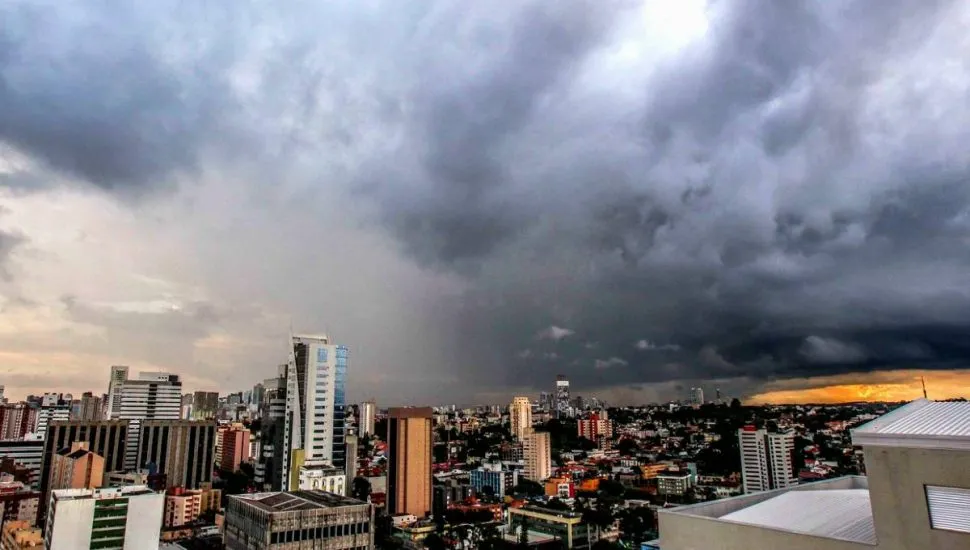 Imagem mostra Curitiba em uma visão ampla, com uma grande nuvem de tempestade se aproximando.