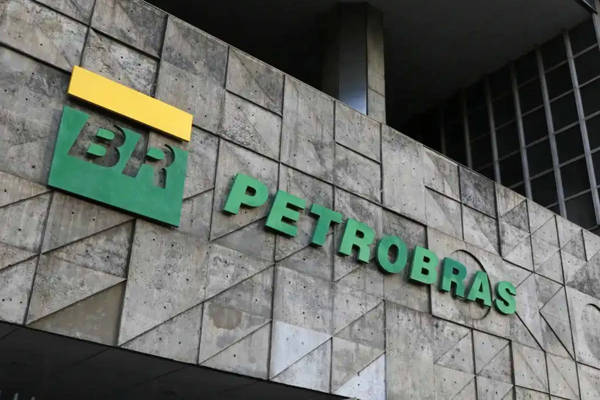 Imagem mostra a fachada da uma unidade da Petrobras, com letras em verde coladas em uma parede de pedra. Há um detalhe em amarelo em cima do "BR".