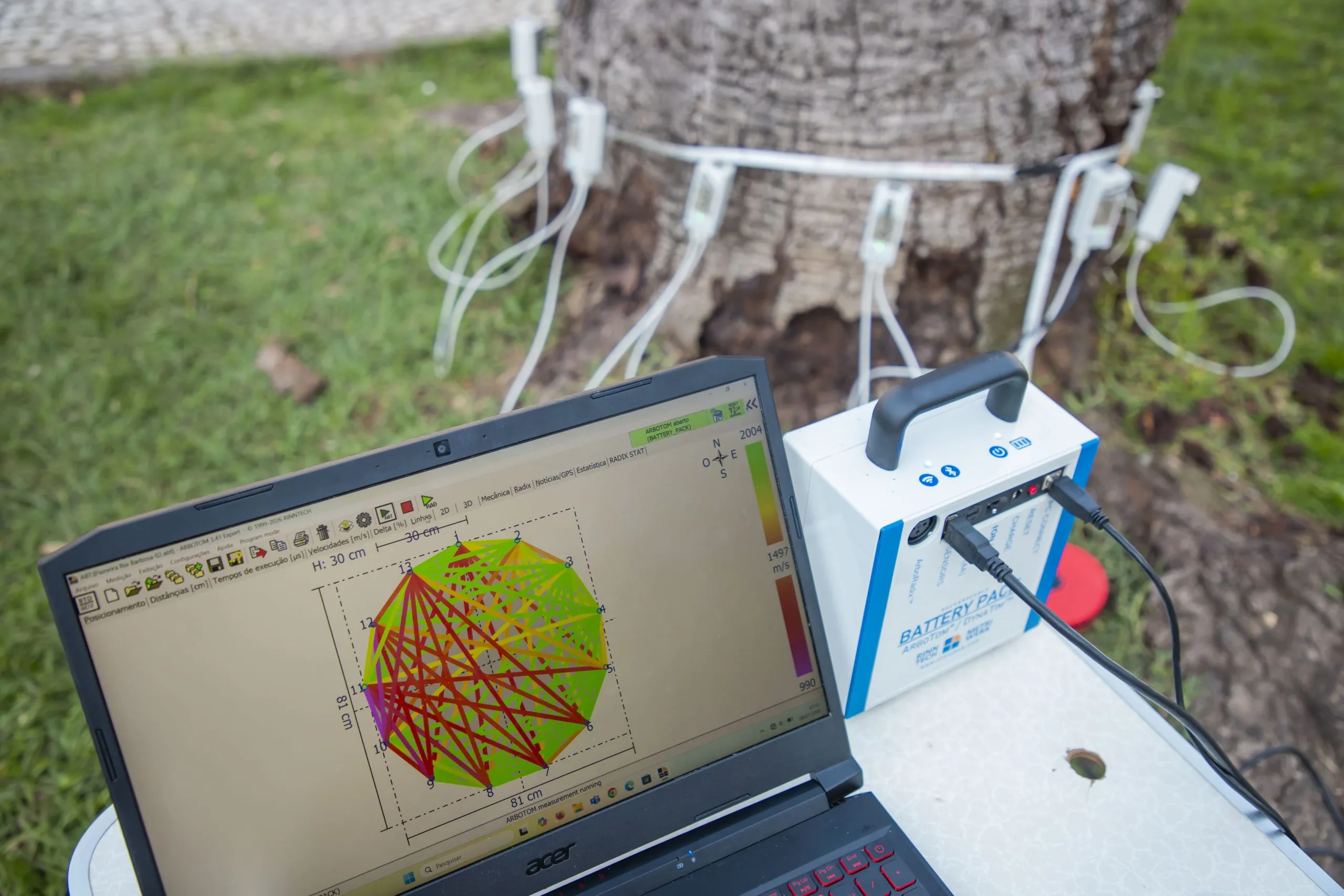 Imagem mostra notebook com equipamento específico ligado ao tronco de uma árvore
