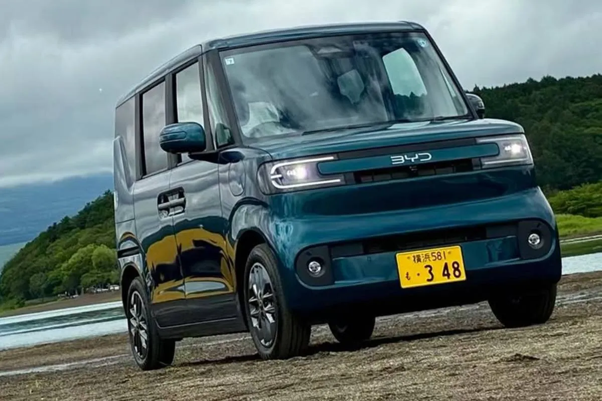 Imagem mostra a parte externa da frente do novo BYD Racco na cor verde. Detalhe mostra a grade frontal, amplo para-brisa e uma placa amarela, típica do Japão.