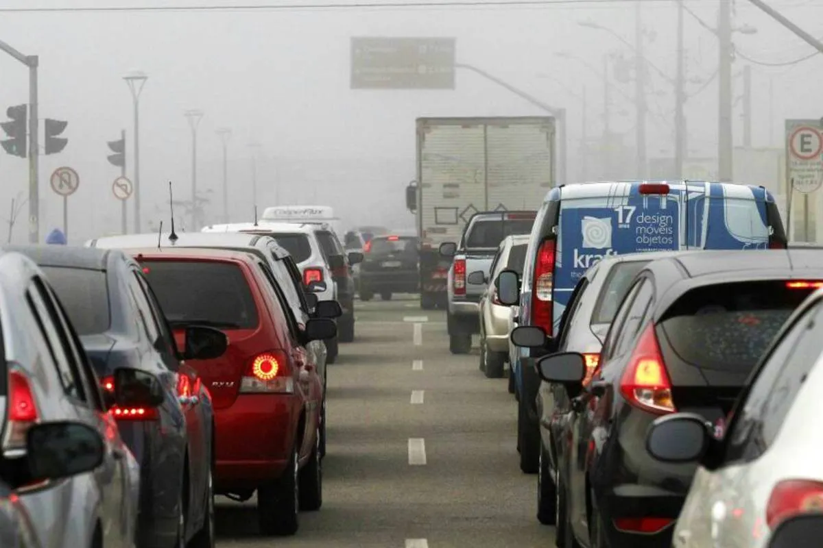 Imagem mostra carros parados em uma manhã de neblina em Curitiba. No meio um corredor entre as faixas e aos lados carros de diversas cores engarrafados.