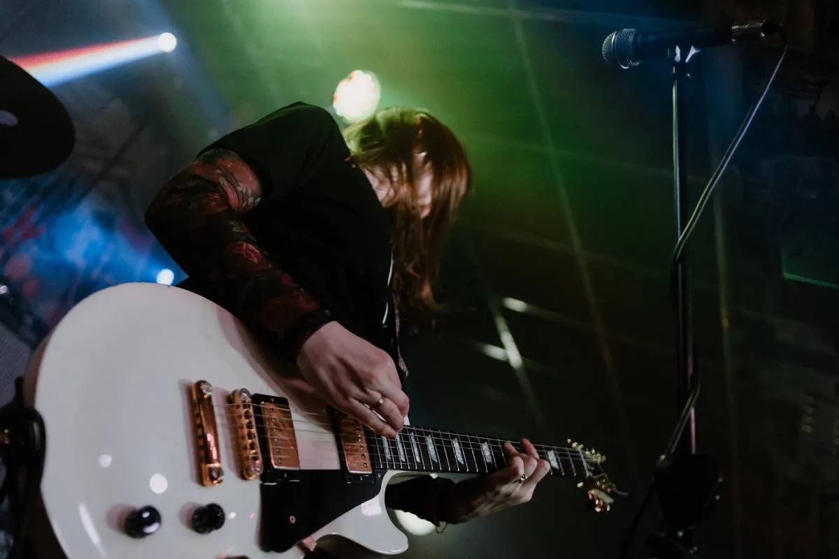 Imagem mostra um guitarrista emo durante um show.