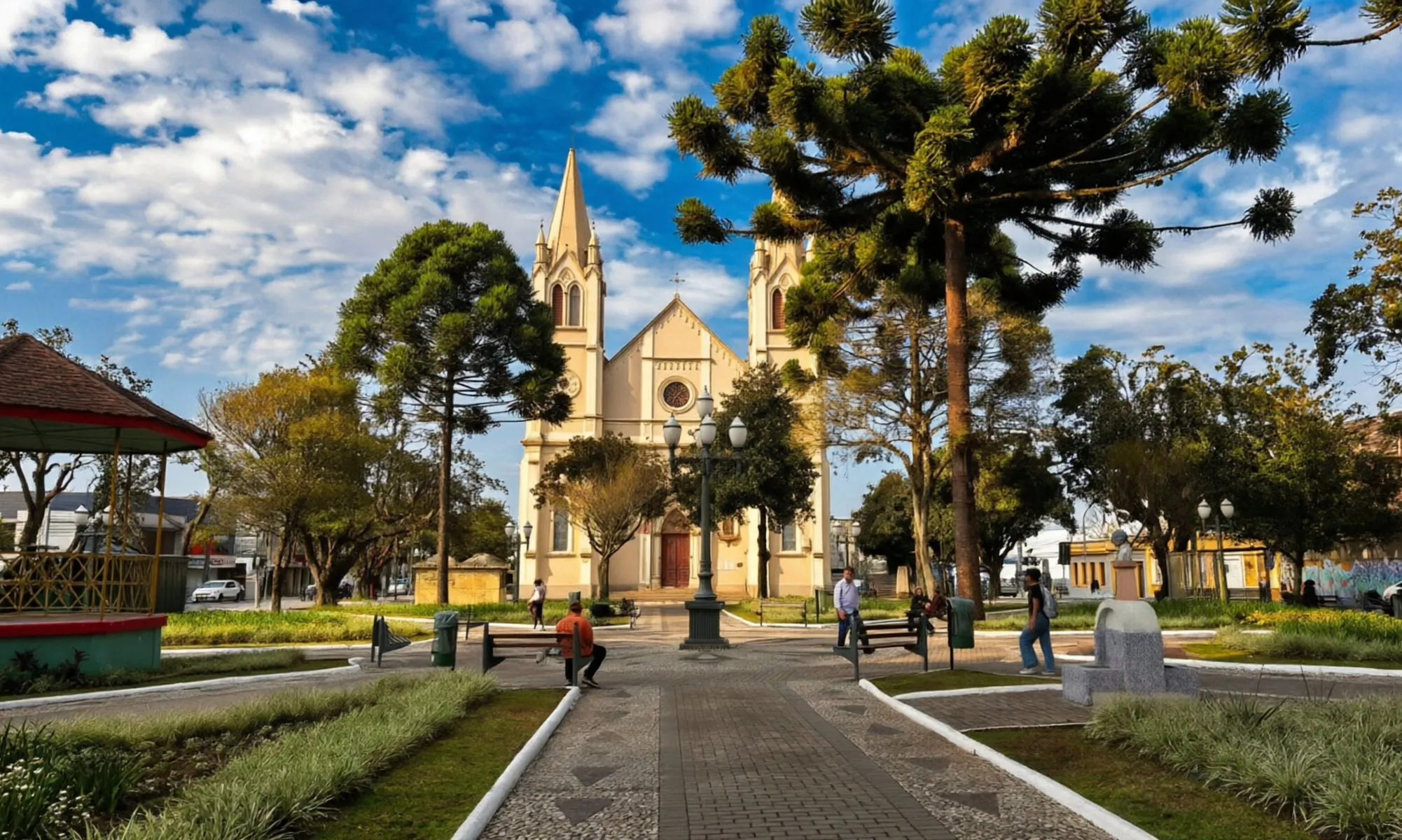 imagem mostra igreja principal da praça central de Campo largo com muitas árvores e araucárias