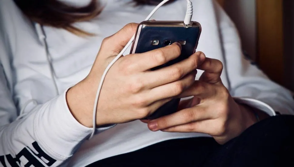 Imagem mostra uma pessoa segurando um celular na mão.