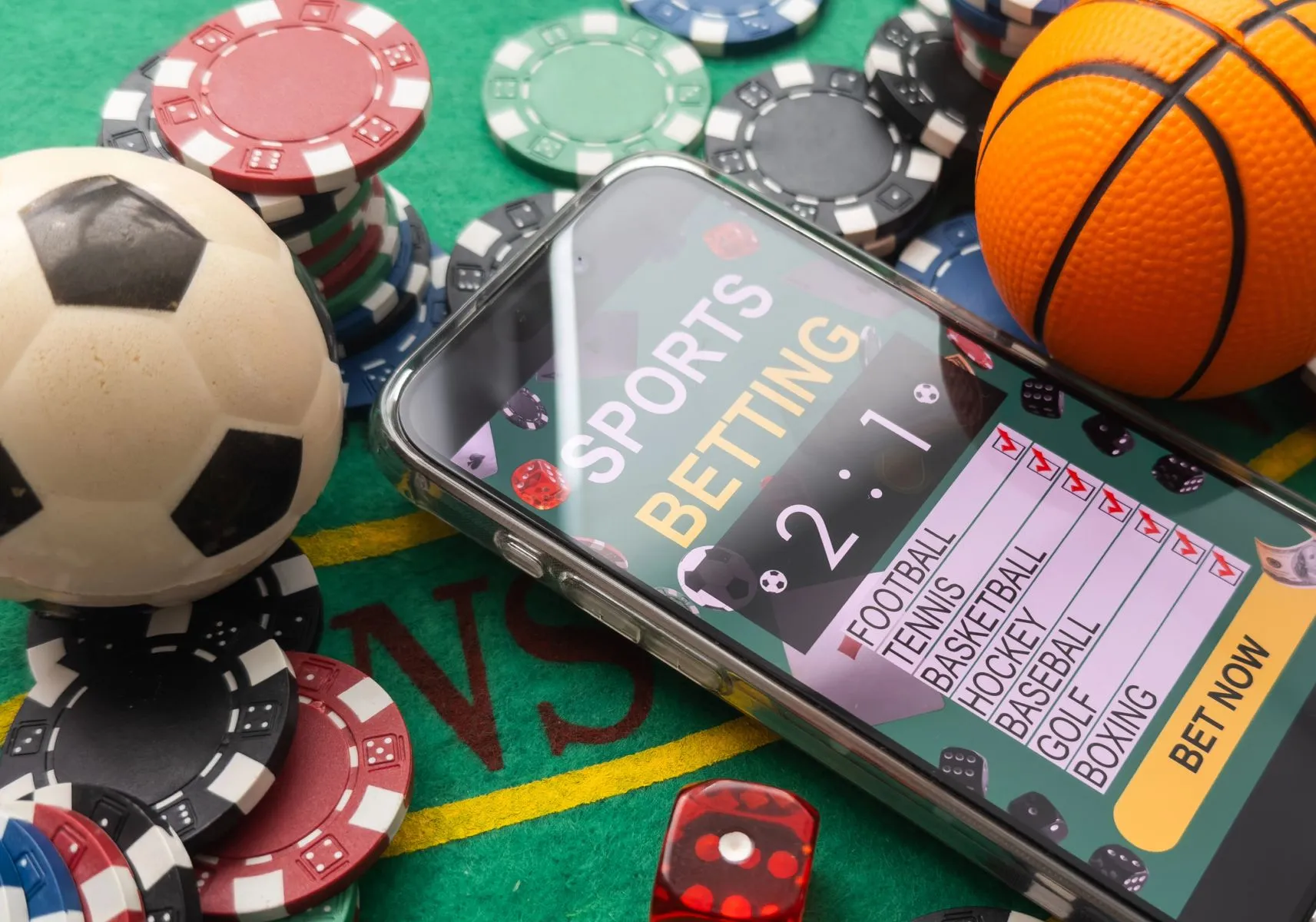 Imagem mostra um celular logado em um site ficticio de apostas, com fichas e dados espalhados e bolas de futebol e basquete