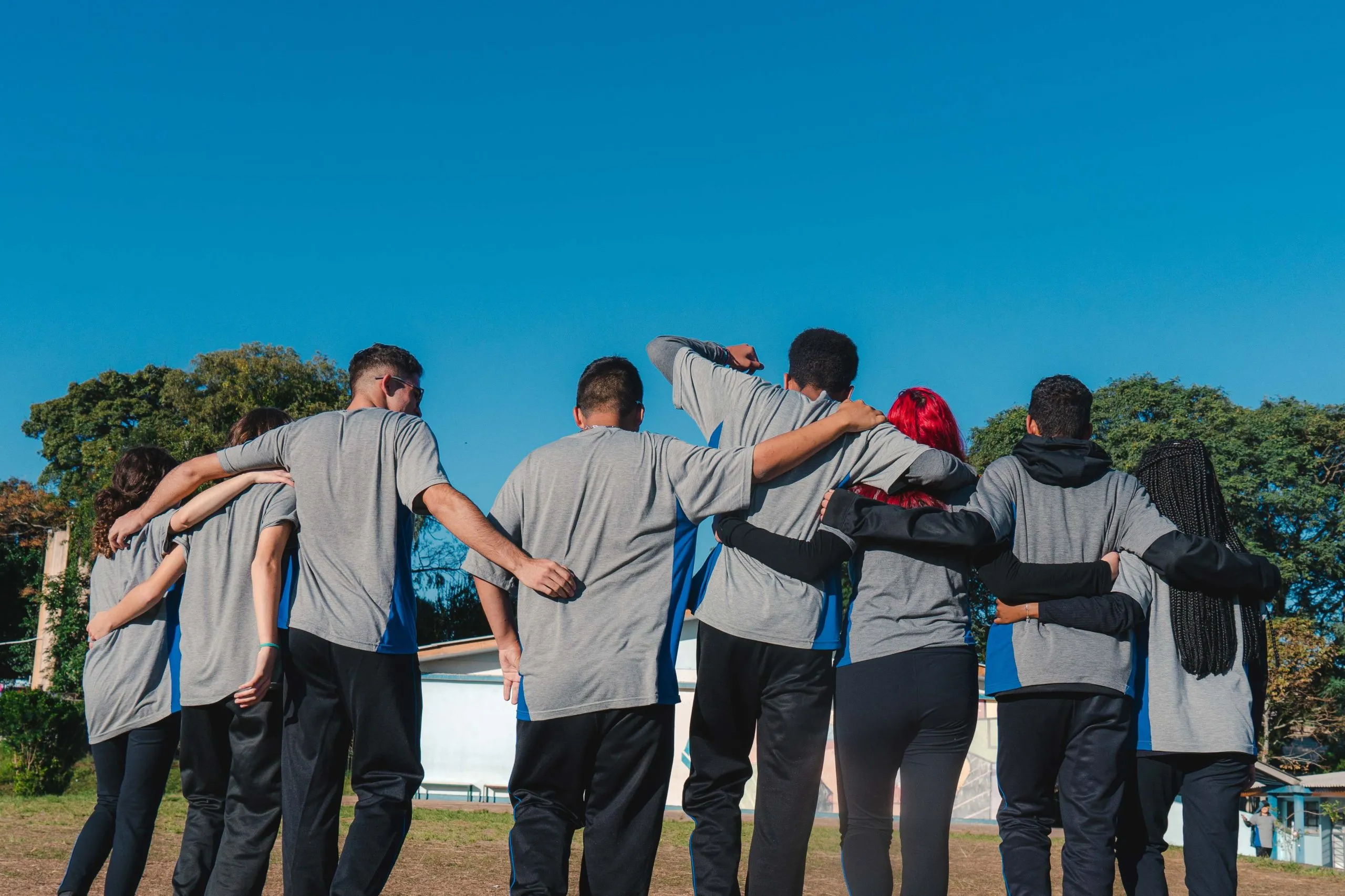 A imagem mostra um grupo de estudantes paranaenses de costas, caminhando abraçados.