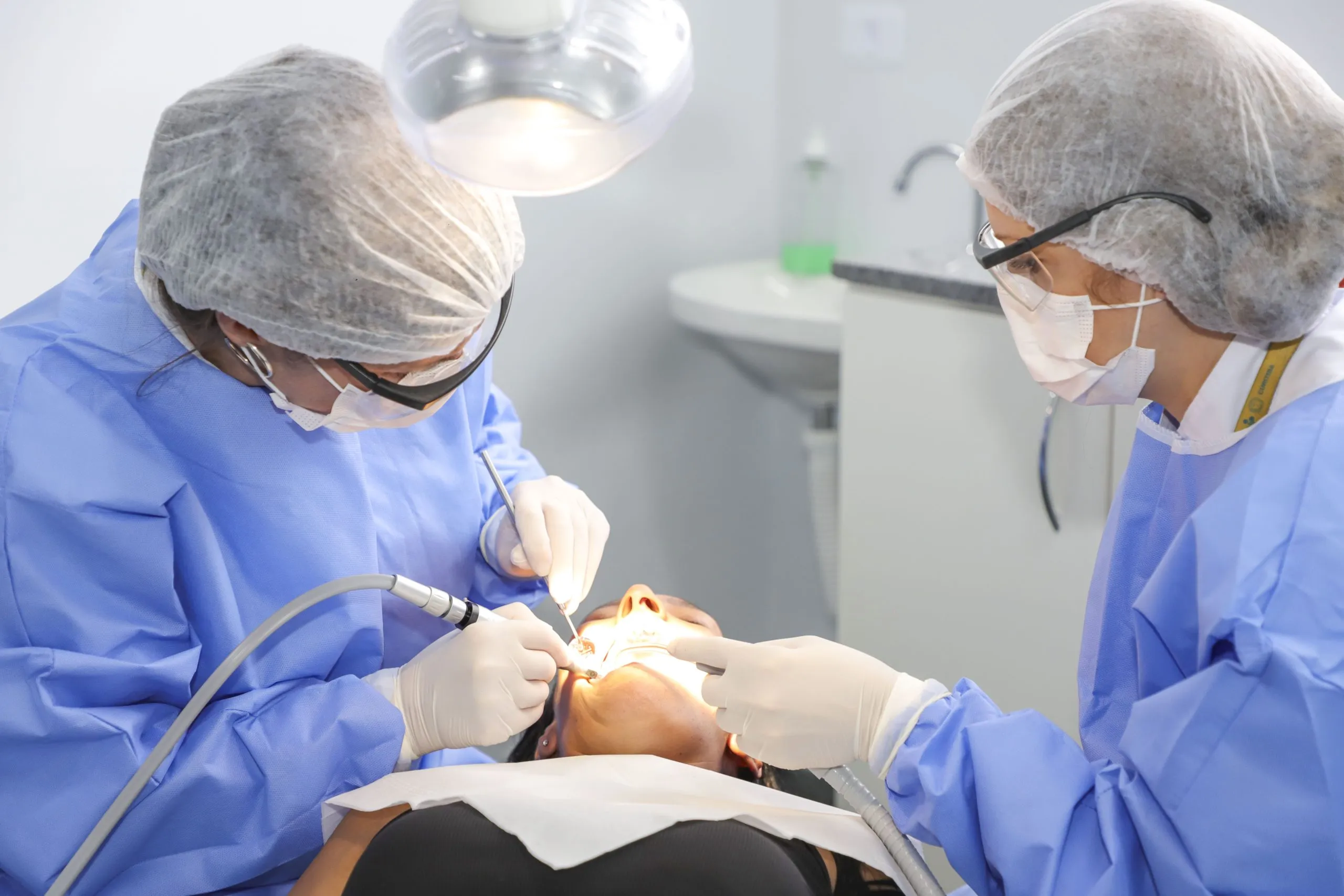 A imagem mostra uma mulher recebendo atendimento odontológico na Unidade de Saúde Mãe Curitibana.