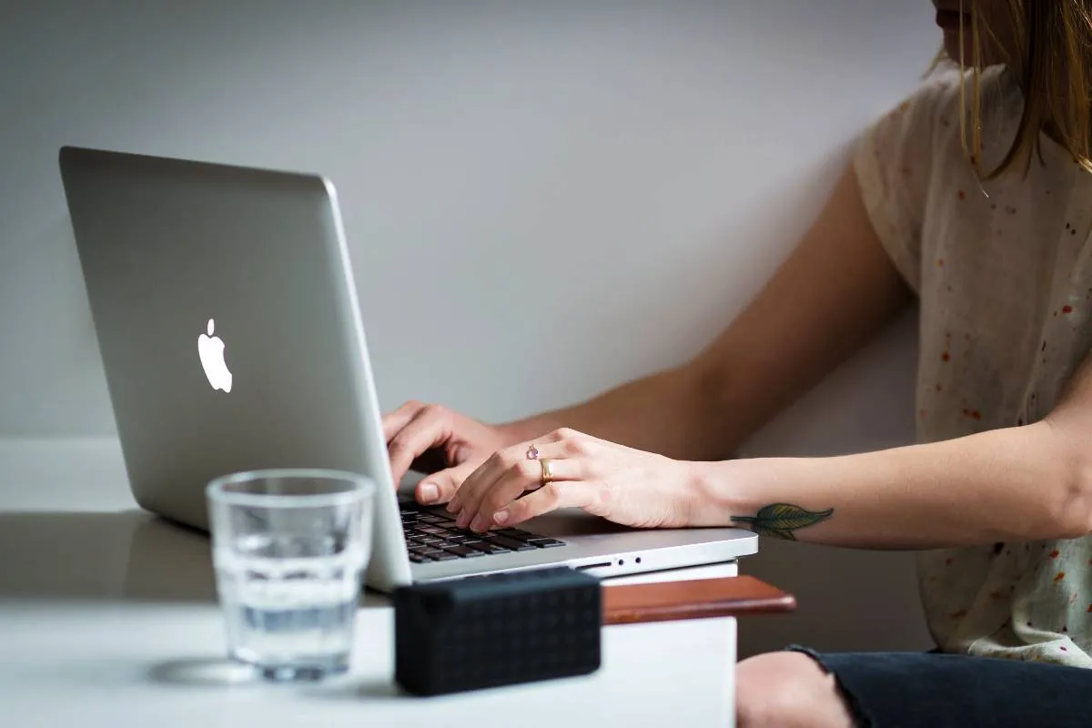 Imagem mostra uma mulher acessando um computador cinza da Apple.