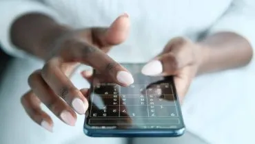 Imagem mostra uma mulher jogando Sudoku online pelo celular.