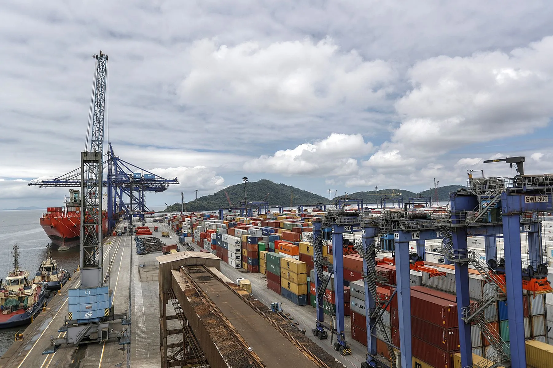Imagem mostra navio atracado no porto, com centenas de containers no pátio