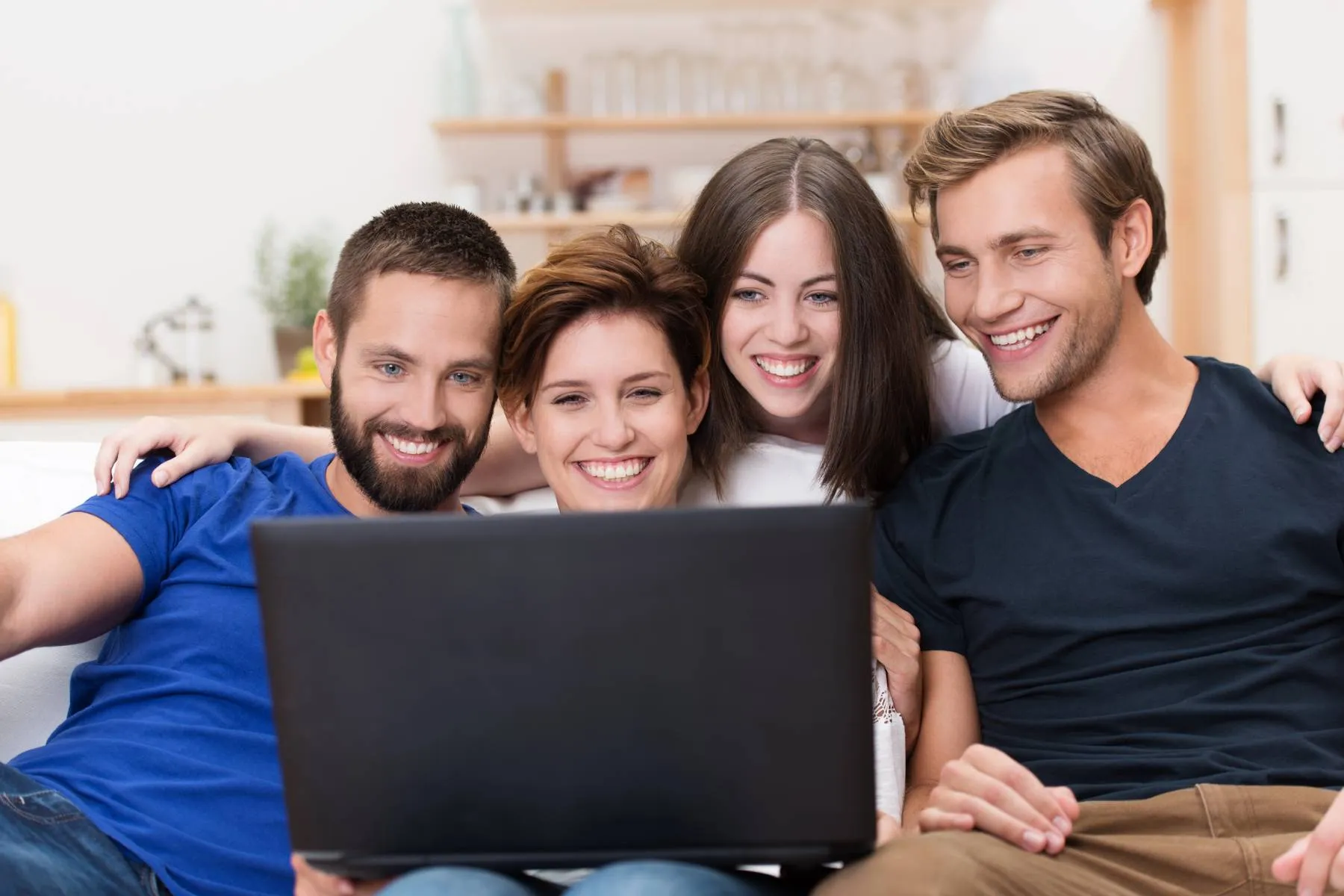 Imagem mostra um grupo de pessoas olhando uma tela de notebook.