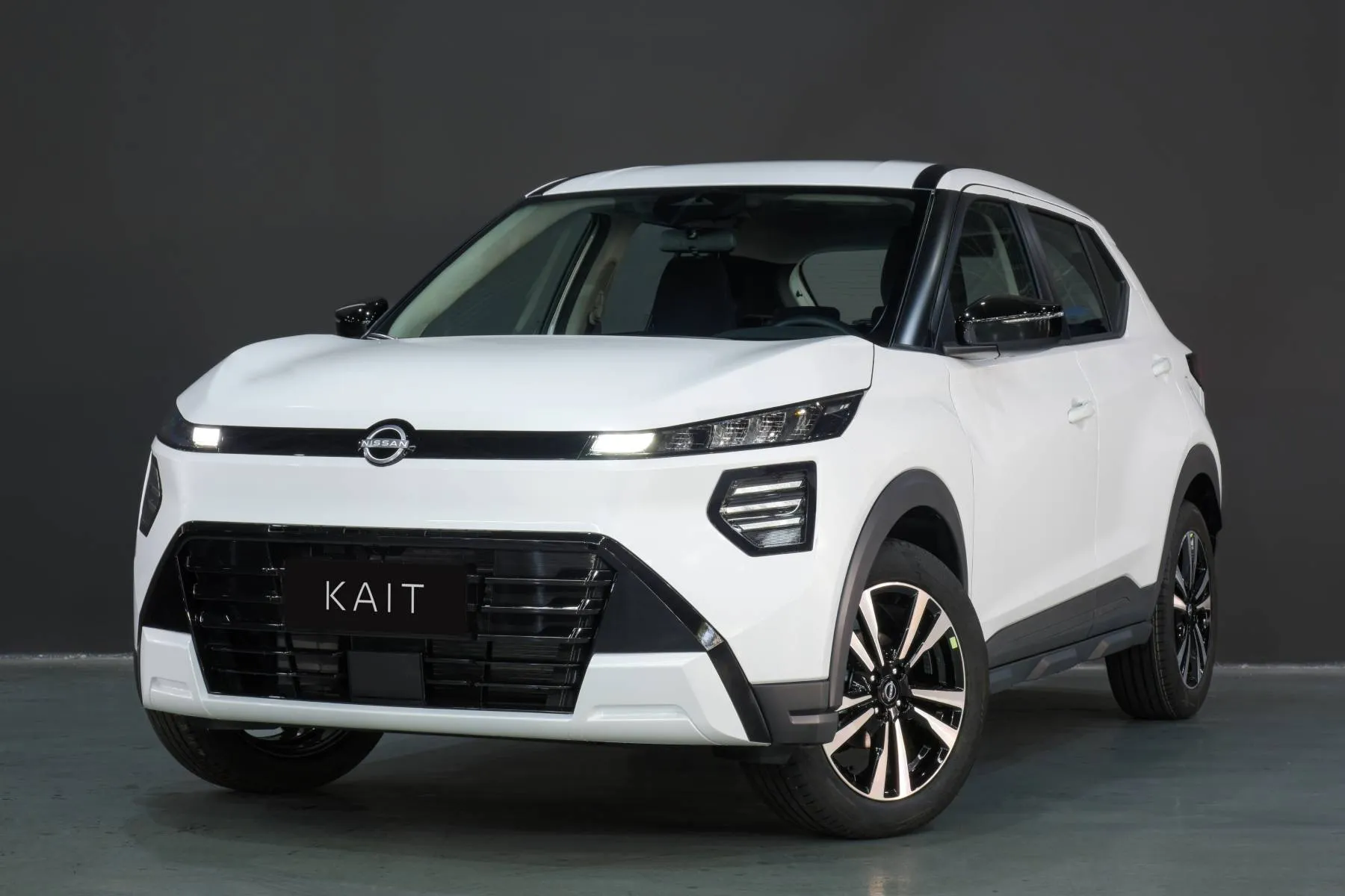 Nissan Kait dianteira lateral na cor branca 2027. Grade frontal do Nissan Kait exibe o conjunto óptico separado com faróis em iluminação full LED de longo alcance.