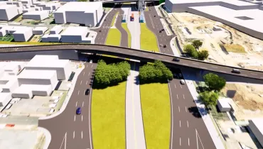 Renderização tridimensional em vista aérea de um projeto arquitetônico e viário urbano. A imagem exibe uma complexa infraestrutura de trânsito composta por um viaduto curvo em nível elevado, pistas asfaltadas com múltiplas faixas de tráfego, canteiros centrais gramados e áreas arborizadas. Ao centro, há uma canaleta exclusiva para ônibus e uma estação-tubo de transporte coletivo. Em torno do complexo viário, alinham-se quarteirões com maquetes brancas de edificações comerciais e residenciais, além de áreas de terreno sob iluminação simulada de dia ensolarado.