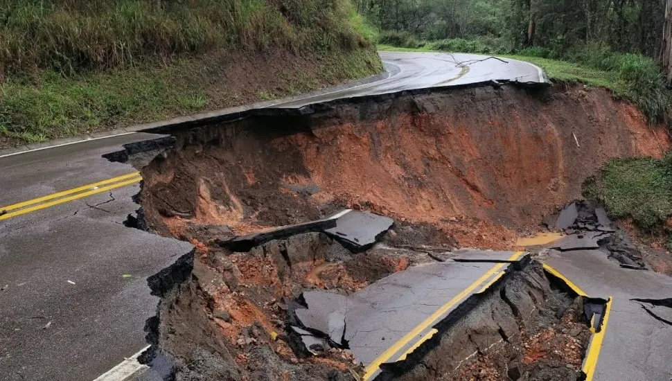 A foto mostra o asfalto da rodovia totalmente desmoronado, entre pedaços de concreto e terra molhada.