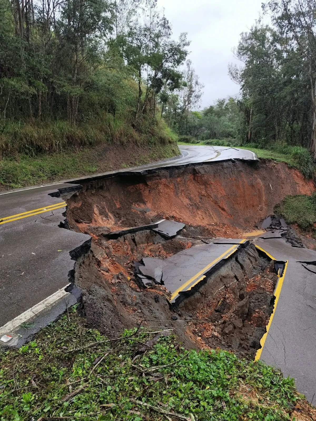 A foto mostra o asfalto da rodovia totalmente desmoronado, entre pedaços de concreto e terra molhada.