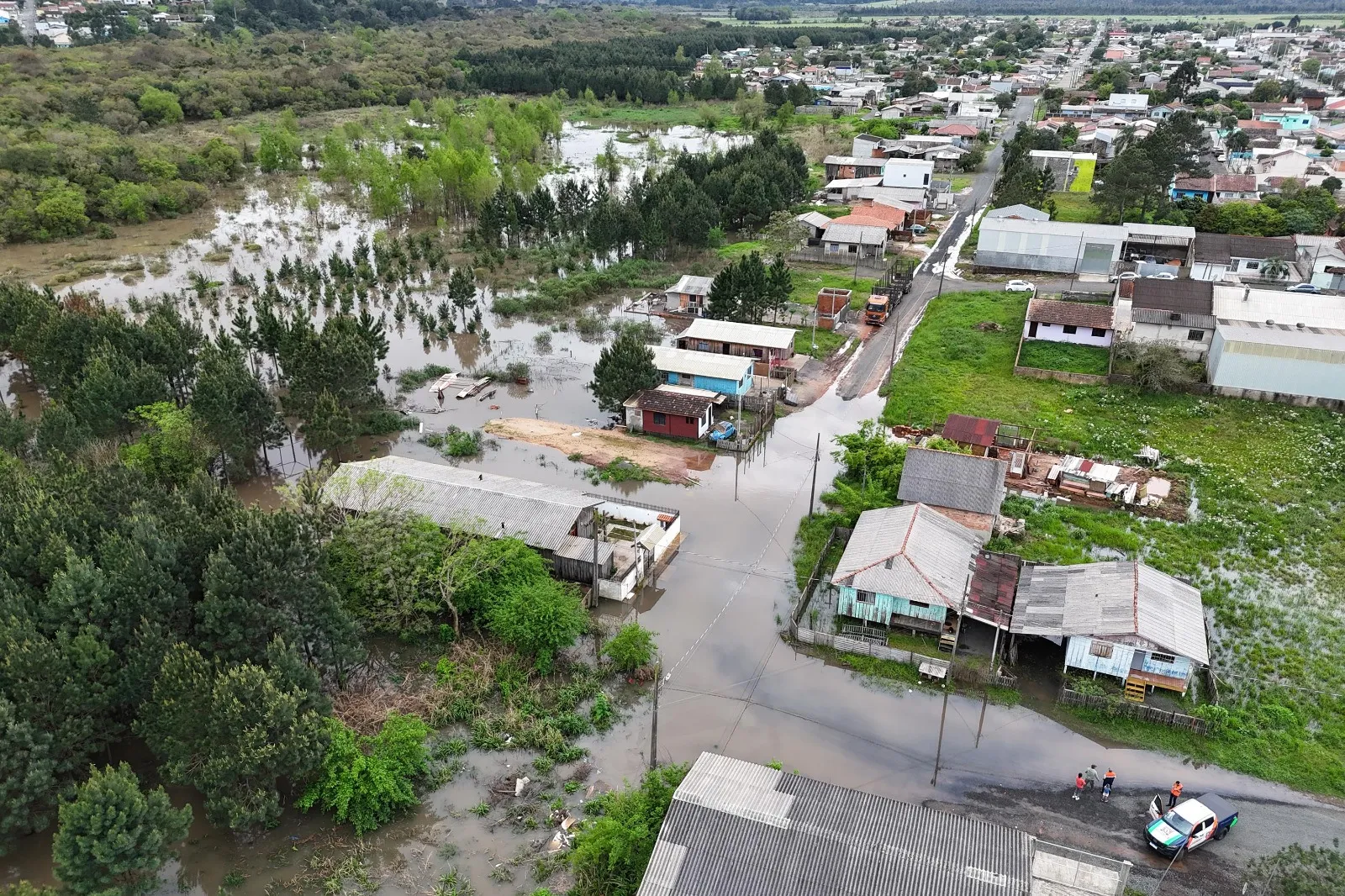 A foto mostra várias casas, ruas e árvores tomadas pela água.