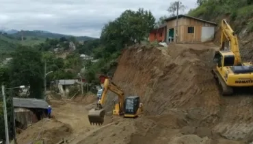 A imagem mostra máquinas trabalhando na desobstrução de vias para serviços de religamento de energia.