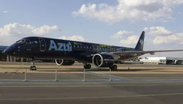 Jato Embraer E2 da Azul com pintura azul-escura na fuselagem. A aeronave está na pista do aeroporto.