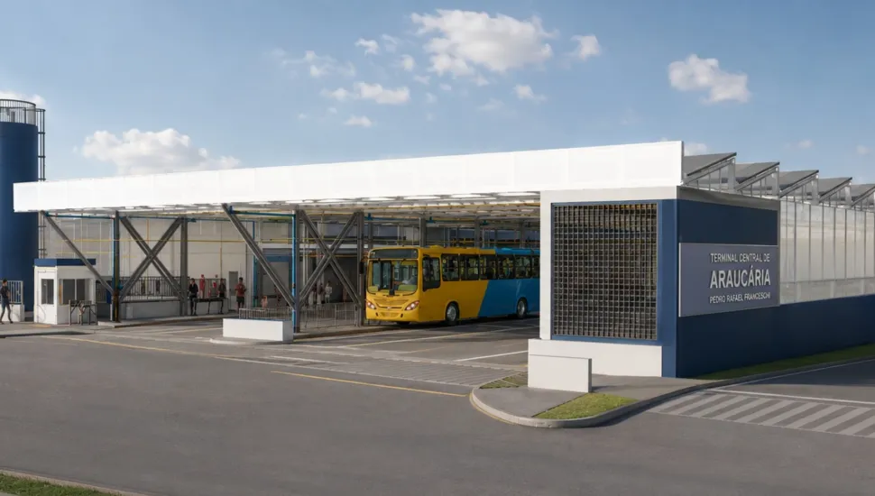 Fotografia em enquadramento amplo com plano geral da fachada e da área de embarque de um terminal de transporte coletivo urbano sob luz diurna natural. Em primeiro plano, estende-se a pista de asfalto cinza-escuro com marcações de faixa de pedestres no canto inferior direito e canteiros de calçada. À direita, destaca-se a estrutura da fachada do terminal, composta por um painel azul-escuro com a inscrição "TERMINAL CENTRAL DE ARAUCÁRIA - PEDRO RAFAEL FRANCESCHI" em letras maiúsculas brancas. No plano intermediário, sob a cobertura metálica de marquise branca sustentada por vigas treliçadas cinzas, um ônibus urbano nas cores amarela e azul está estacionado na plataforma de embarque. Pessoas transitam pelas calçadas e plataformas ao fundo da estrutura, próximo a uma guarita de controle à esquerda. Ao fundo, à esquerda, observa-se um reservatório ou caixa d'água cilíndrica azul, enquanto o teto do terminal apresenta estrutura de dentes de serra (sheds) sob um céu azul-claro com poucas nuvens brancas e dispersas.