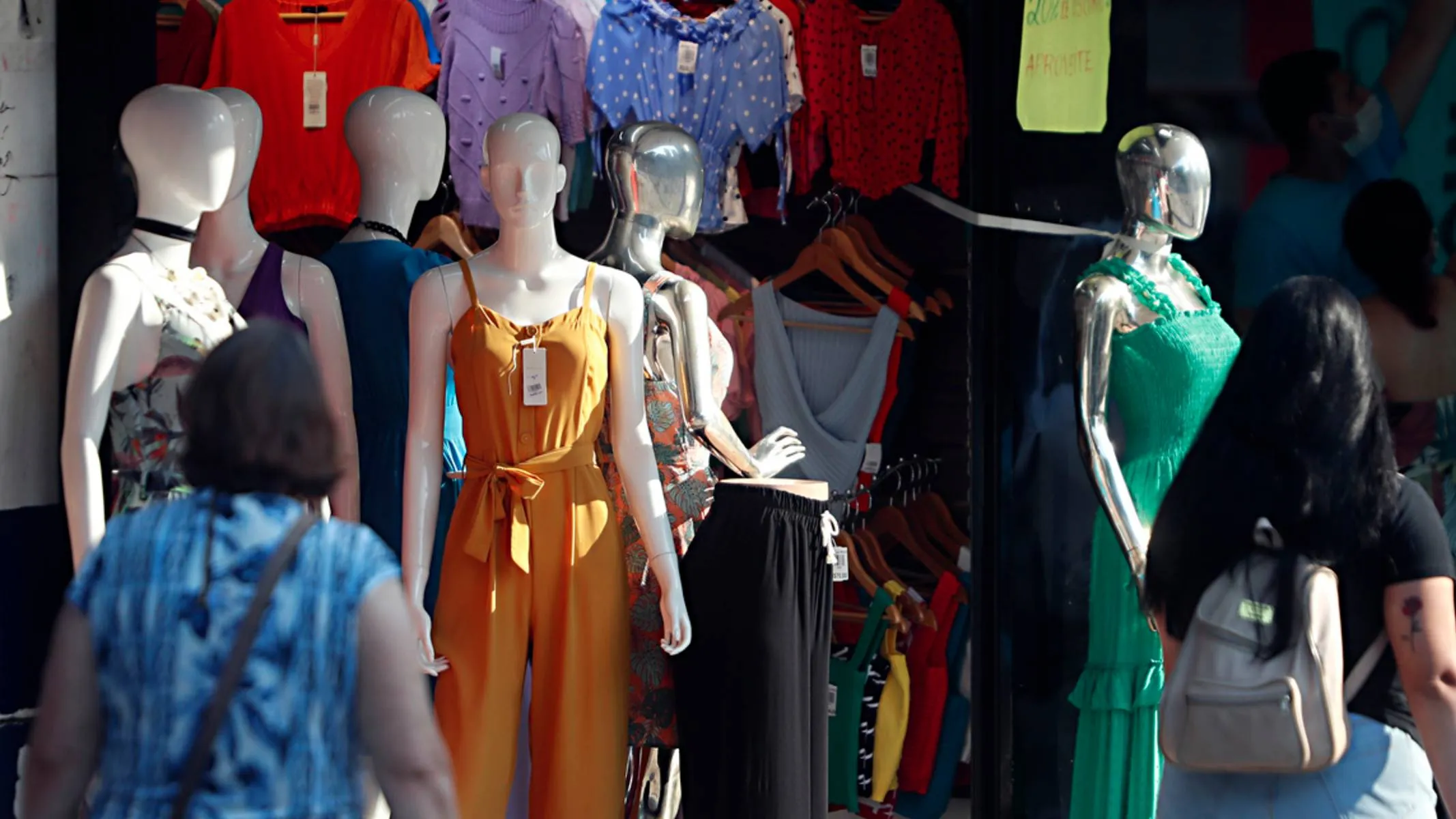 Imagem mostra clientes olhando uma loja de roupas.