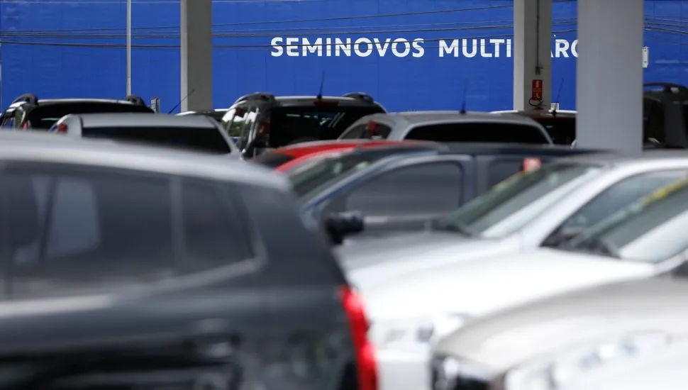 Imagem mostra uma revenda de carros usados.