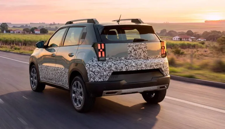 Novo Fiat Argo X: Imagem mostra a traseira do novo carro da Fiat, com detalhes para as lanternas, hack de teto, rodas e parte da lataria ainda camuflada.