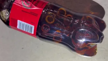 Fotografia de uma garrafa de refrigerante com ampolas de medicamentos para emagrecer dentro do líquido.