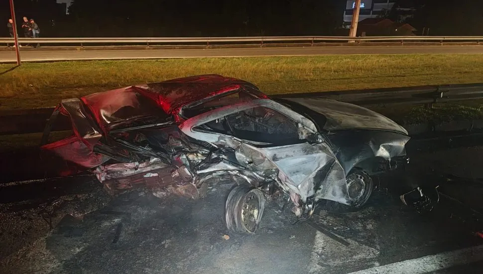 Fotografia de um veículo queimado às margens de uma rodovia.