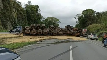 A imagem mostra o caminhão tombado.