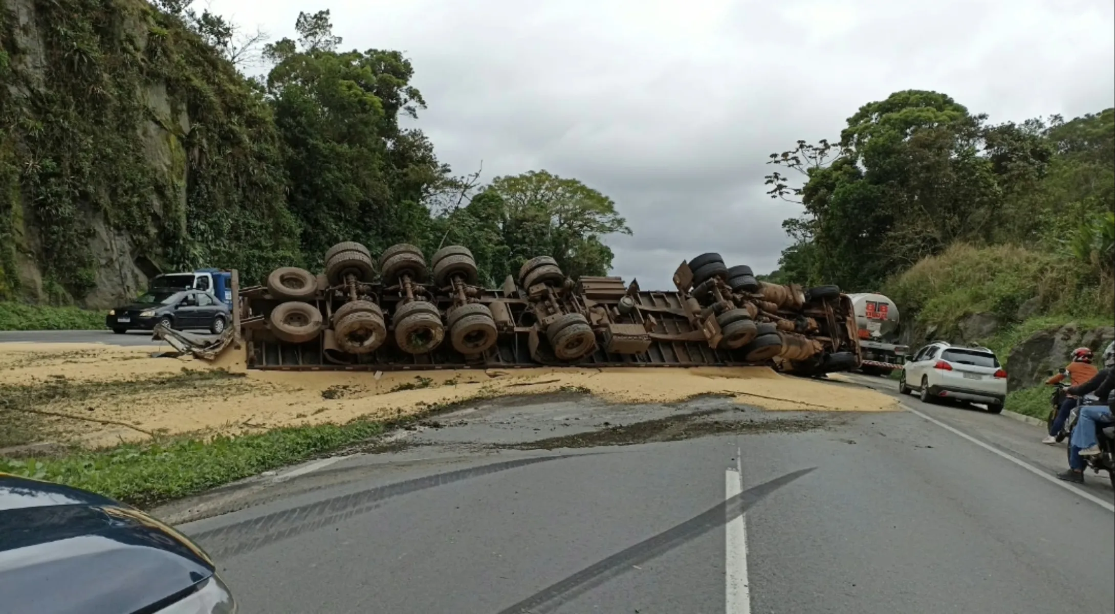 A imagem mostra o caminhão tombado.