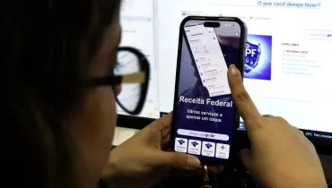 Imagem mostra uma mulher utilizando um aplicativo da Receita Federal.