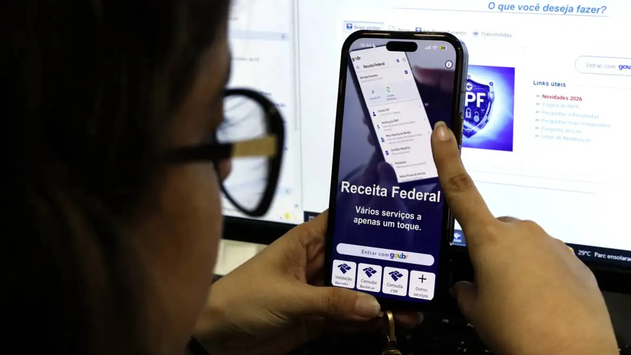 Imagem mostra uma mulher utilizando um aplicativo da Receita Federal.