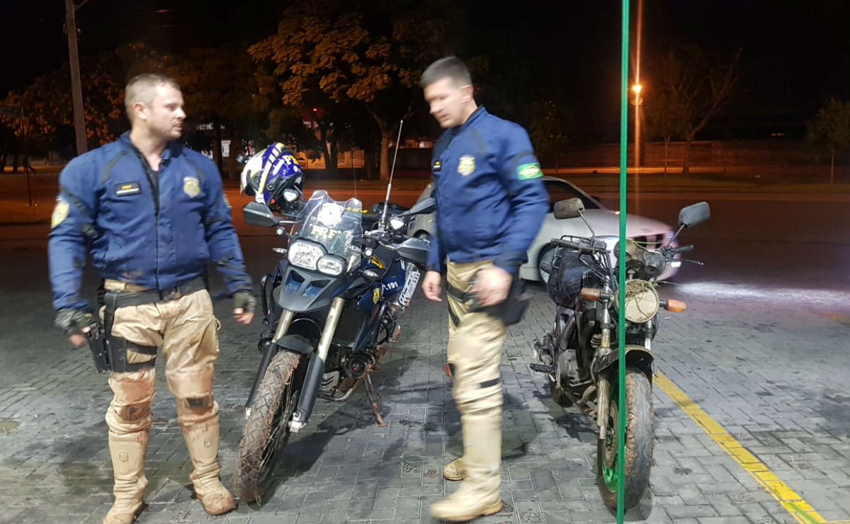 Policiais com a moto usada na fuga.Foto: Divulgação/PRF