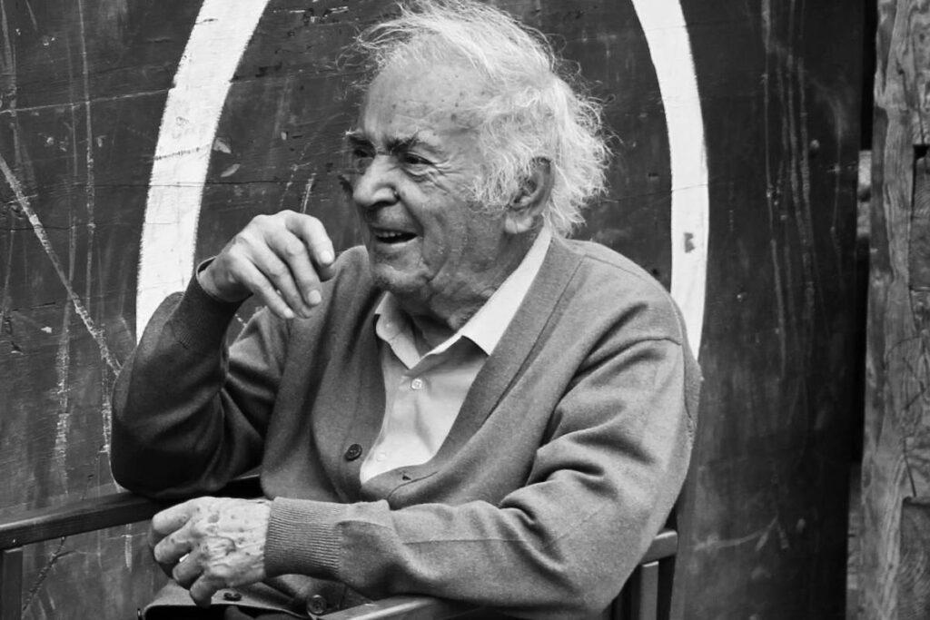 Imagem mostra um idoso rindo com seus amigo em uma mesa